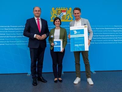 Finanz- und Heimatminister Albert Füracker übergibt Förderbescheid an Carina Bläser (Projektmanagerin fabuly) und Philipp Wollbeck (stellvertretende Geschäftsführung der LAG) (Bild: StMFH/Christian Blaschka)